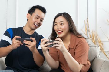 a man and woman sitting on a couch looking at a cell phone